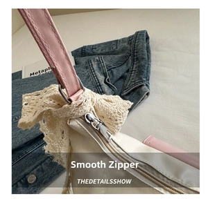 Detail of metal zipper and lace bow accessory on a white and pink tote bag