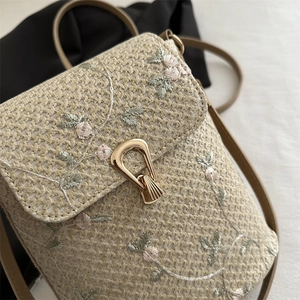 Straw bucket bag with delicate floral embroidery and gold U-shaped metal lock closure