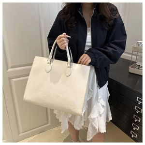 Detail of white crocodile embossed tote bag featuring sturdy handles and spacious design
