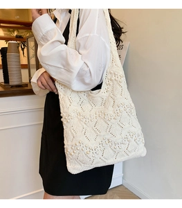 Detail of white hollow pearl knit tote bag showing the textured weave and shoulder fit