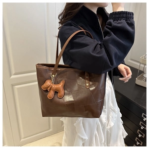 Détail du grand sac cabas marron avec breloque chien en cuir et texture grainée