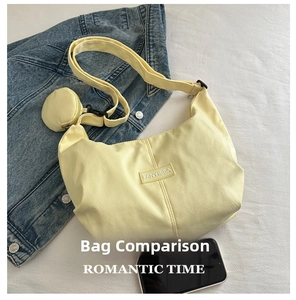 Detail of light yellow tote bag with round coin purse and adjustable strap next to a phone