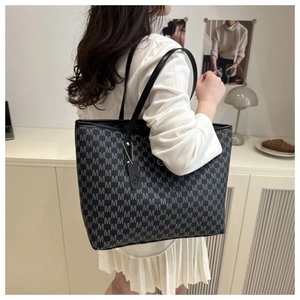 Detail of large tote bag with M-letter monogram print and stylish decorative logo tag