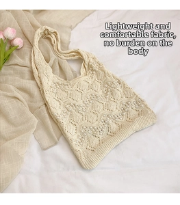 Detail of hollow knit tote bag featuring woven pearls on soft creamy white fabric