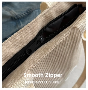 Detail of beige corduroy fabric texture and smooth black zipper on a small tote bag