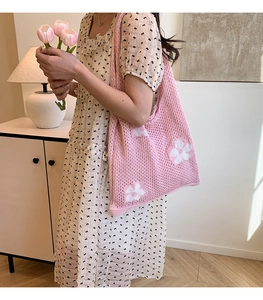 Close-up of pink knit tote bag with white floral pattern on a female model shoulder
