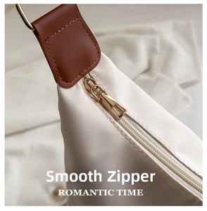 Detailed close-up of the smooth golden metal zipper and beige nylon fabric of the tote