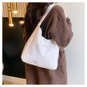 Detail of a large white vintage tote bag on model's shoulder with smooth matte leather texture