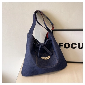 Detail of dark blue denim tote with decorative bow and floral print strap lining