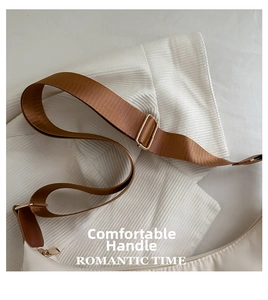 Detail of adjustable brown nylon strap and gold hardware on white crescent bag