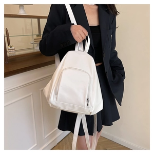 Close-up of a white minimalist backpack with front zipper pocket on a black blazer