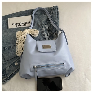 Detailansicht der hellblauen Tragetasche mit Metallschnalle und Spitzenschleife auf Denim