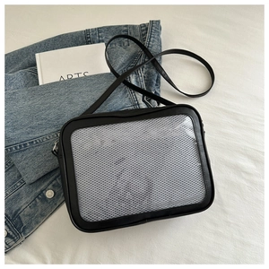 Close-up of black crossbody bag with transparent mesh pocket on a blue denim jacket