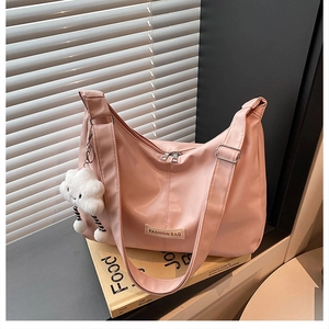 Sac fourre-tout rose en nylon avec étiquette mode et breloque nuage blanc sur un livre