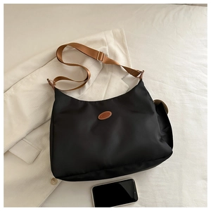 Détail du sac fourre-tout noir en oxford avec écusson en cuir et bandoulière
