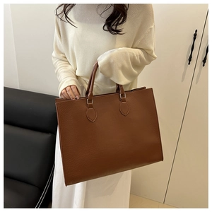 Close-up of brown crocodile embossed tote bag texture with metallic handle hardware