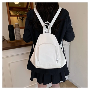 Detail showing white minimalist backpack with front zipper pocket on model's back
