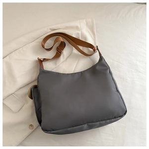 Détail de la bandoulière marron réglable et du tissu en nylon gris avec ferrures en métal