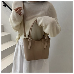 Detail of a chic beige bucket bag with vertical textured patterns and gold hardware