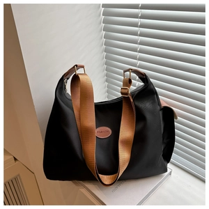 Détail du sac cabas en nylon noir avec écusson en cuir et bandoulière réglable