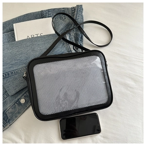 Minimalist black mesh crossbody bag with leather trim and slim strap on white fabric