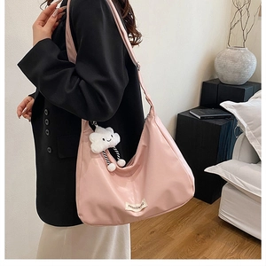 Grand sac hobo rose avec breloque nuage en peluche blanche porté par un mannequin en blazer