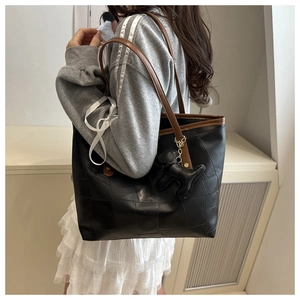 Détail du sac cabas bicolore avec lanières marron et un pendentif en forme de chien