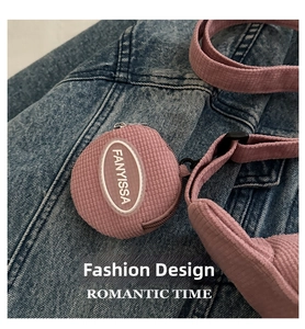 Detail of pink corduroy dumpling bag with FANYISSA logo patch on denim background