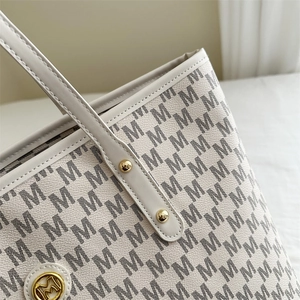 White faux leather tote bag with black M monogram pattern and gold metal hardware details