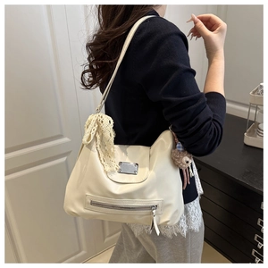 Detailansicht der cremefarbenen Ledertasche mit Spitzenschleife und Plüschbär-Anhänger