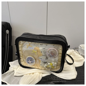 Detail of black ita bag featuring a clear PVC window with anime badges and lace trim