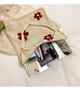Détail du sac cabas en tricot beige à fleurs rouges montrant l'espace intérieur généreux