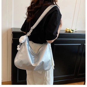 Détail du sac hobo argenté métallisé avec étiquette de mode et pompon en peluche