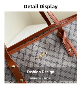 Detailansicht der grauen Canvas-Tote mit braunem Lederbesatz und goldenem Metalllogo