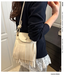Side view of cream tassel crossbody bag with round buckle on female model