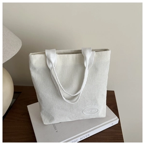 Close-up of white corduroy tote bag showing fine vertical stripes and brand label