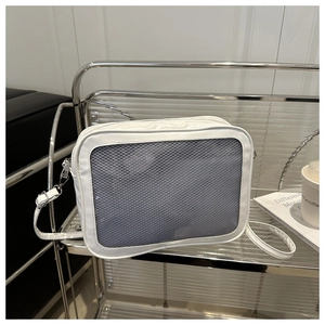 White mesh crossbody tote with adjustable strap displayed on a metal shelf