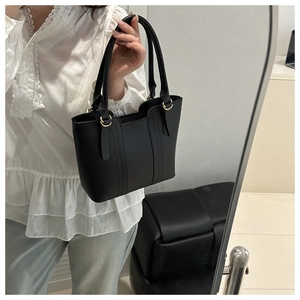 Detail of black faux leather texture and gold ring hardware on a minimalist tote bag