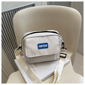 Détail d'un sac bandoulière carré blanc cassé minimaliste avec logo Fanyissa en caoutchouc