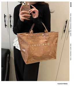 Detail of a large capacity brown tote bag with white TOTE BAG print and waterproof film