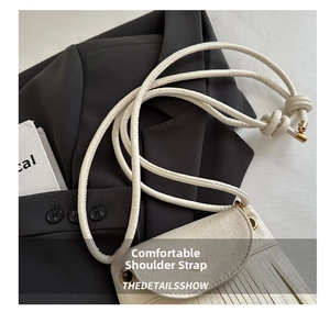 Detail of cream leather crossbody bag featuring tassel fringe and thin cylindrical strap