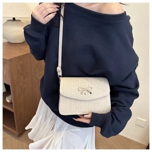 Gros plan du sac bandoulière tissé beige avec boucle papillon dorée élégante