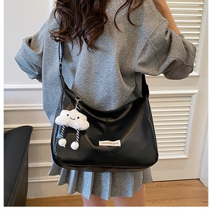 Détail du sac croissant en PU noir avec pendentif nuage et étiquette mode sur mannequin
