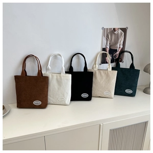 Detail of five corduroy tote bags in brown, cream, black, beige, and dark green colors