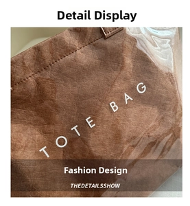 Close-up of brown tote bag with paper texture finish and white lettering detail