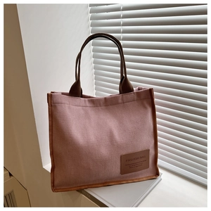Detail of pink knitted tote bag with brown leather patch and textured fabric surface