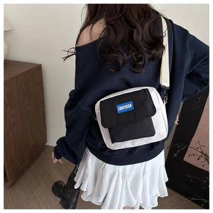 Detail of the two-tone canvas crossbody bag with adjustable strap and blue logo patch