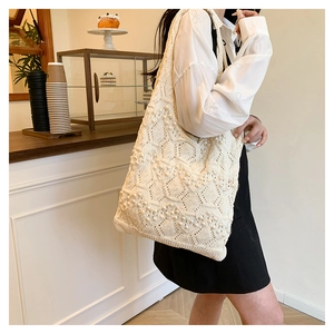 Detailed close-up of ivory knit tote bag featuring elegant faux pearl geometric patterns
