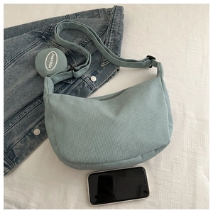 Detail of corduroy dumpling bag with adjustable strap and mini round coin purse pendant