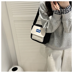 Close-up of black and white canvas crossbody bag with FANTISSA rubber brand logo